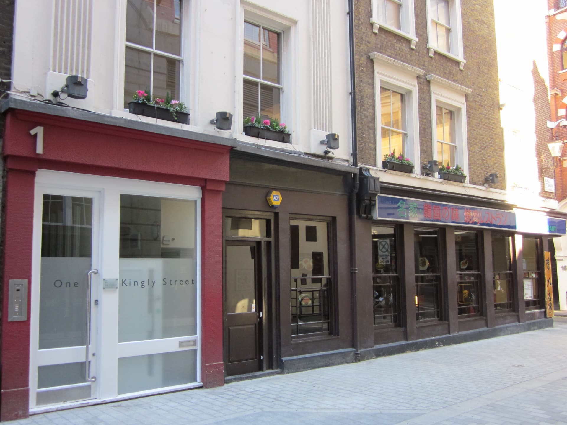 Terraced shopfronts on Kingly Street in Soho, including a red-fronted entrance numbered one and a Korean restaurant