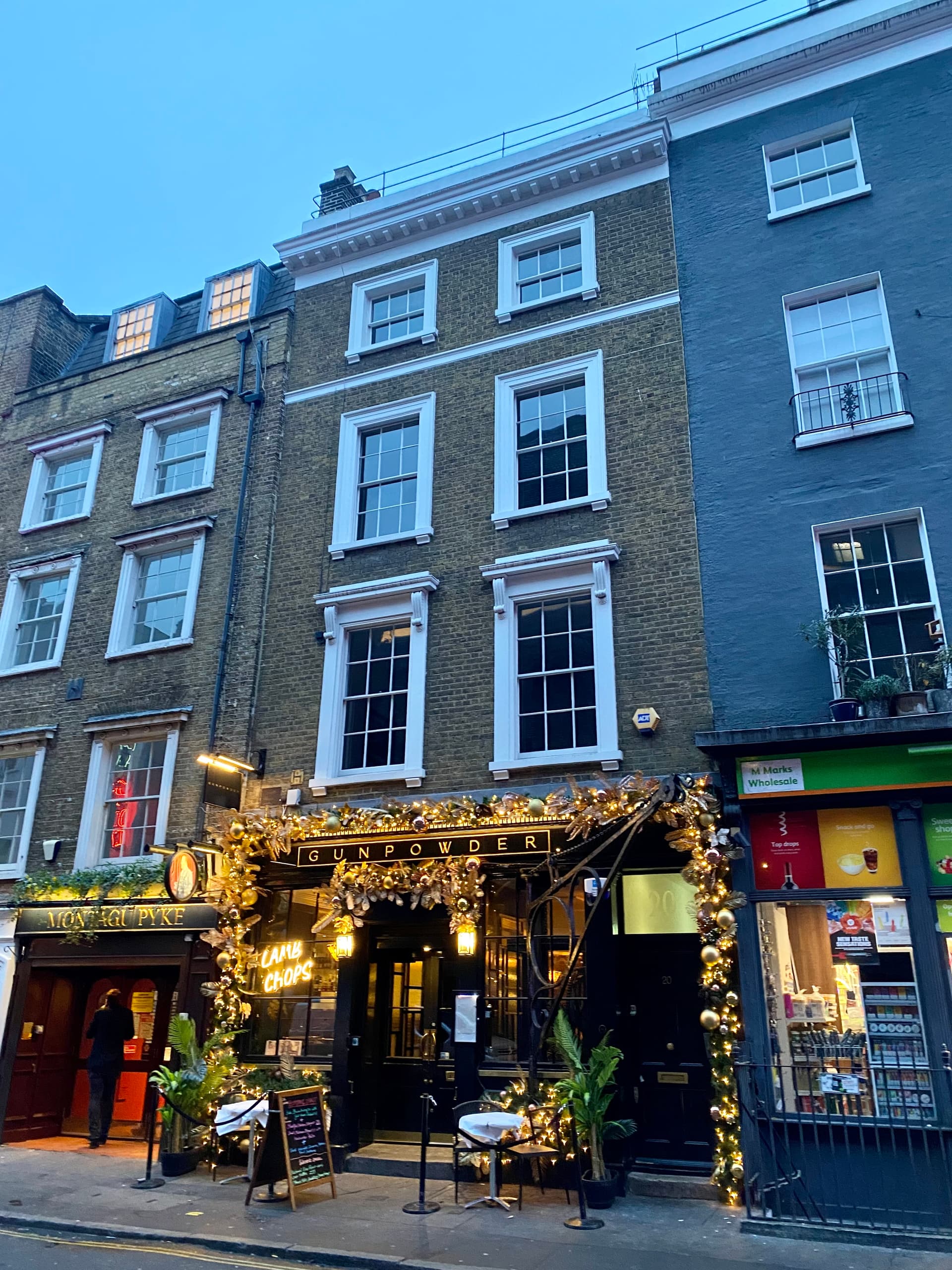 Georgian brick terrace on a Soho street at dusk, with a festively lit restaurant frontage at ground level