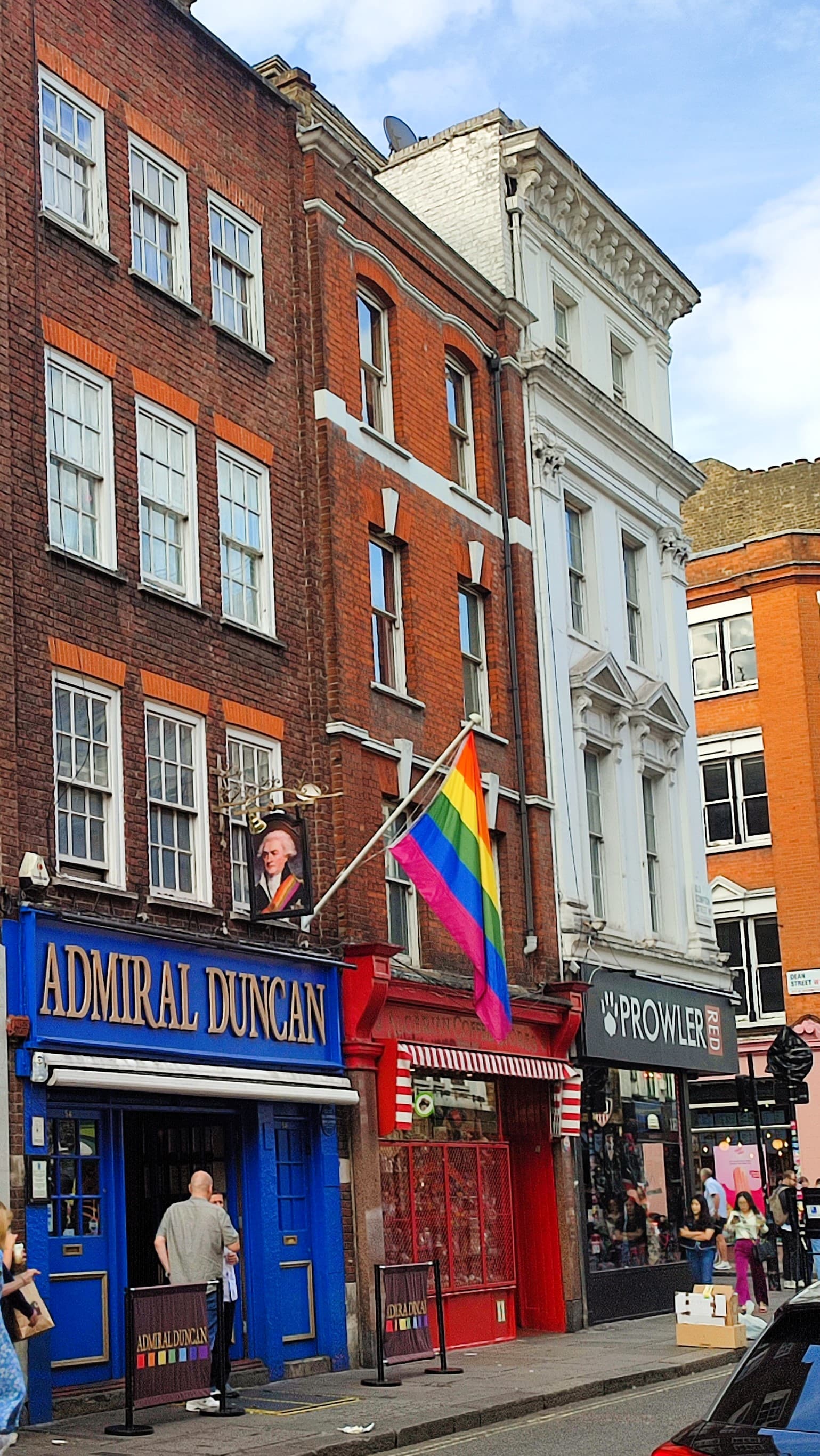 Red Algerian Coffee Stores shopfront beside the Admiral Duncan pub on Old Compton Street, Soho, with a rainbow flag