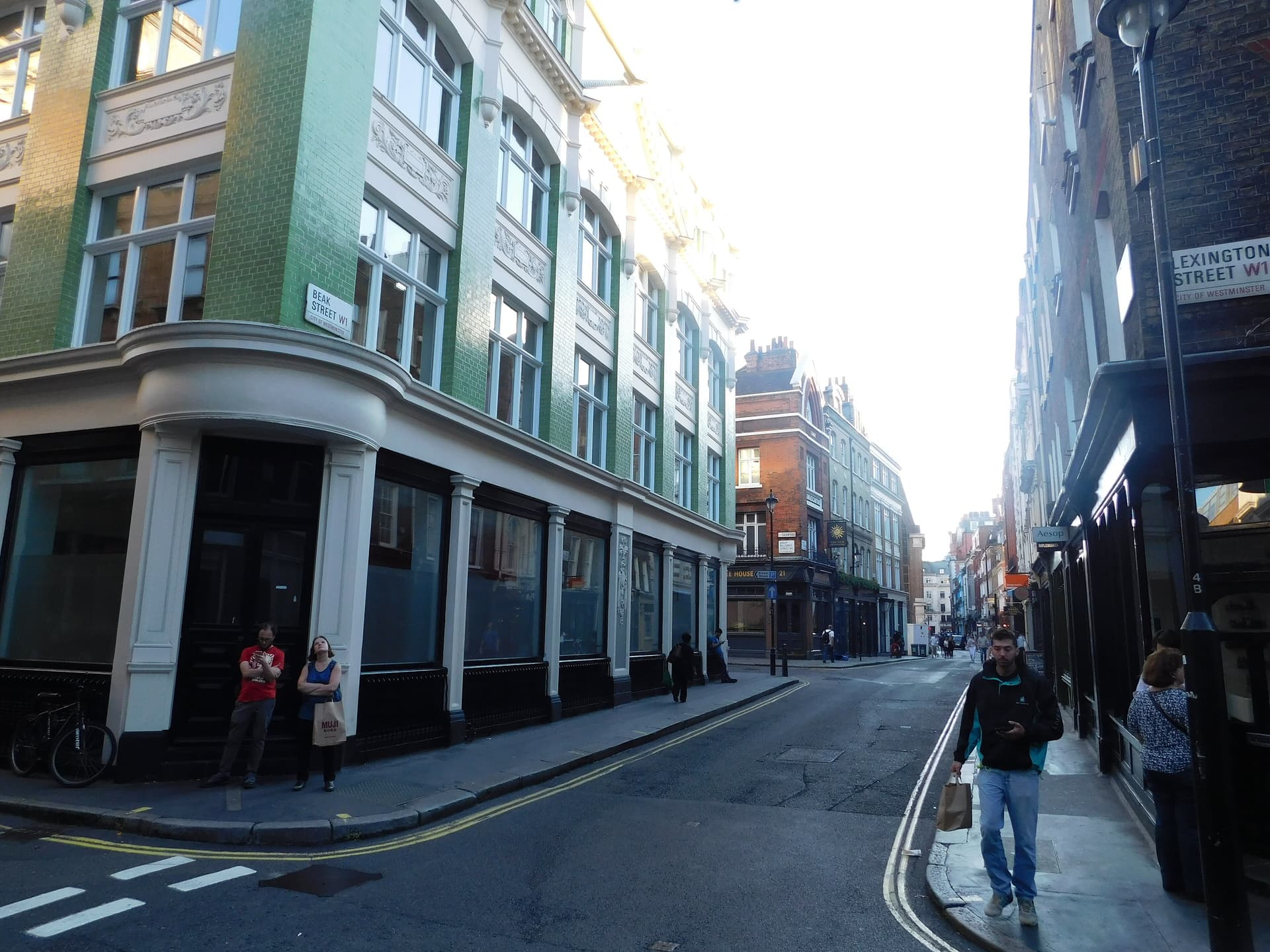 Green-tiled corner building at Beak Street and Lexington Street in Soho, with pedestrians and a pub down the road